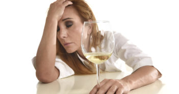 caucasian blond wasted and depressed alcoholic woman drinking white wine glass looking desperate and sad isolated on white in alcohol abuse and addiction and drunk housewife alcoholism problem