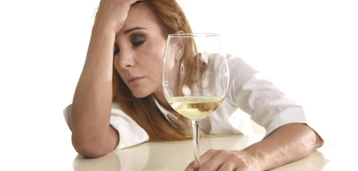 caucasian blond wasted and depressed alcoholic woman drinking white wine glass looking desperate and sad isolated on white in alcohol abuse and addiction and drunk housewife alcoholism problem