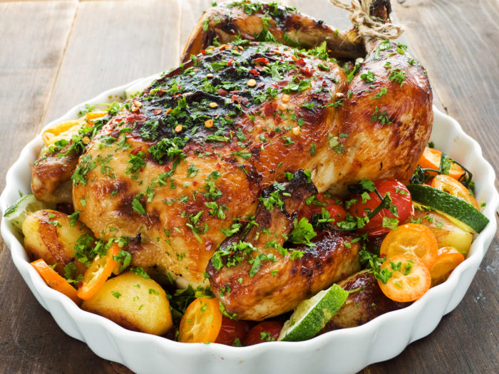 Whole roasted chicken with vegetables, herbs and fruits. Shallow dof.