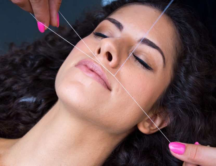 attractive woman in beauty salon on facial hair removal threading procedure