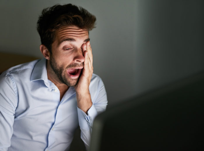 Shot of a tired looking young businessman sitting in front of a computer
