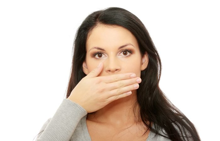 Young woman covering her mouth, isolated on white