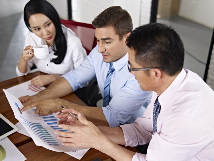 asian and caucasian business executives meeting in office of a multinational company.