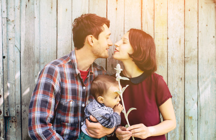 Young family with child posing on the background of an abandoned building