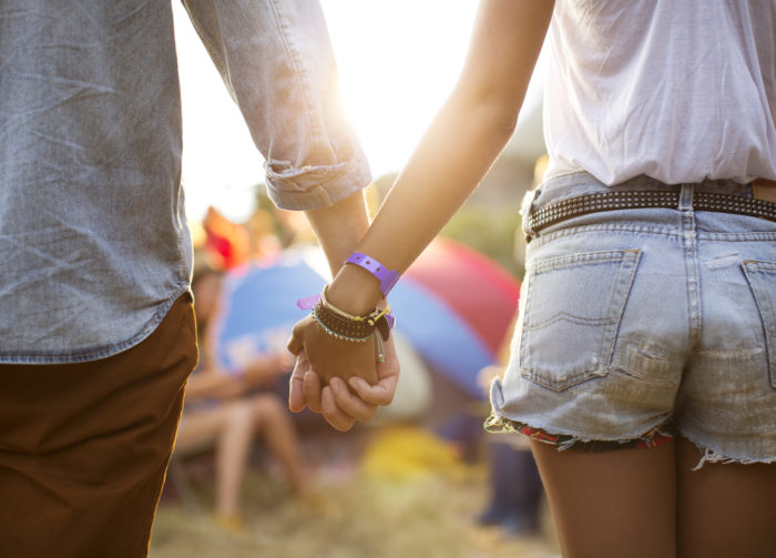 Couple holding hands near tents at music festival