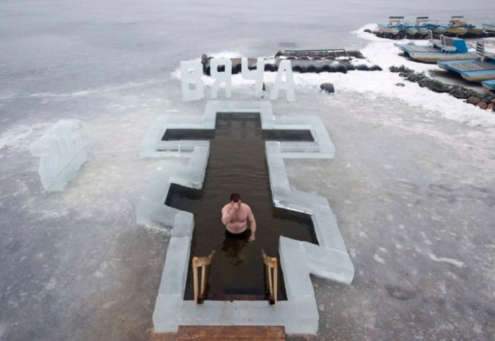 A man crosses himself as he dips into the icy waters of a lake as part of celebrations for Epiphany, near Pilnitsa, northeast of Minsk
