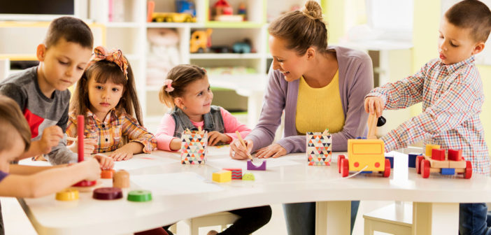 Happy teacher enjoying with group of children at preschool.