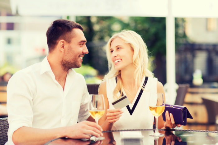 date, people, payment and relations concept - happy couple with credit card, bill and wine glasses at restaurant terrace