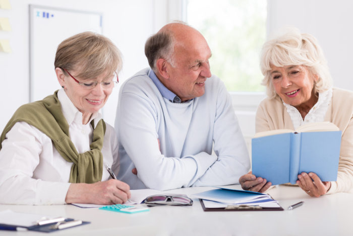 Smiling happy retirees studying at the desk