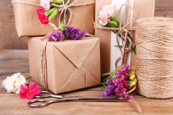 Beautiful gifts with flowers and decorative rope, on old wooden background