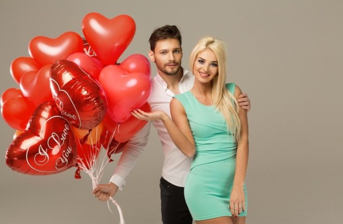 Happy loving couple on grey background with heart balloons