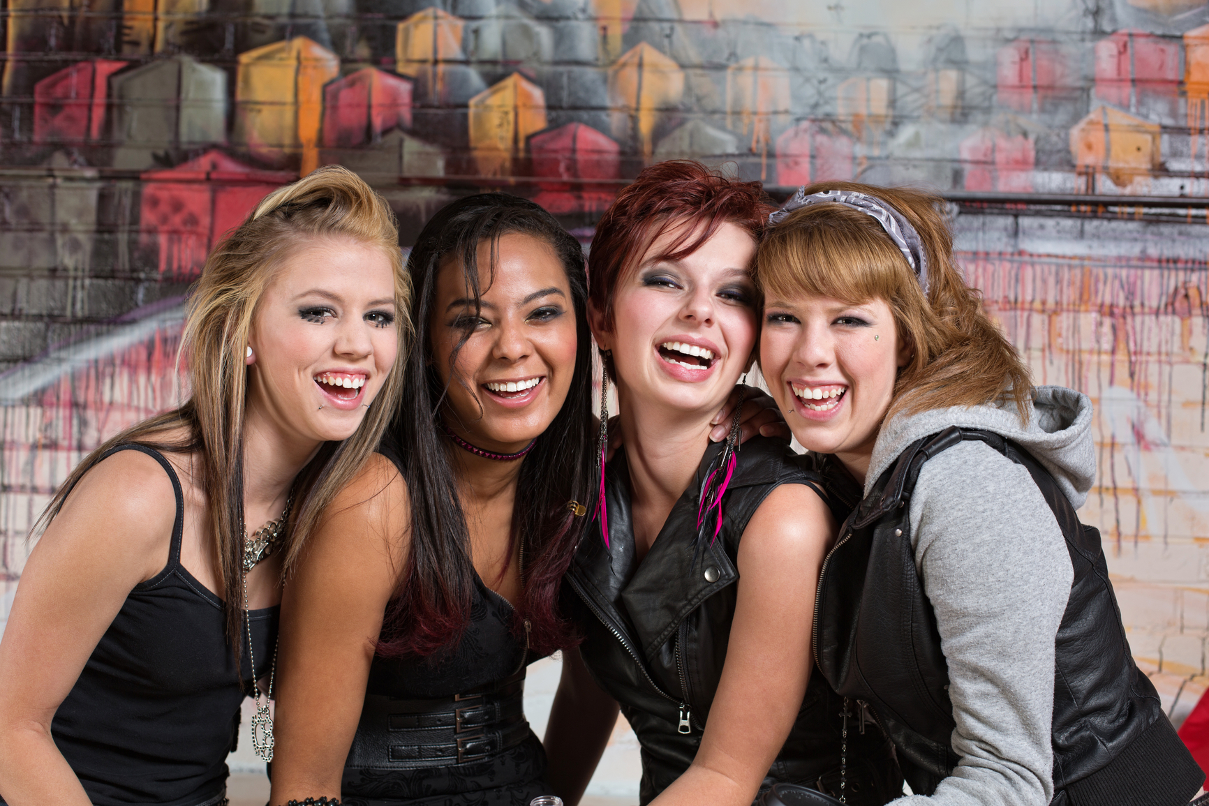 Group of four cute diverse urban teenagers laughing