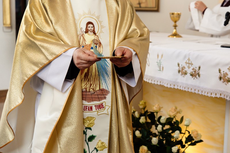 priest holding golden plate for communion at wedding ceremony at church