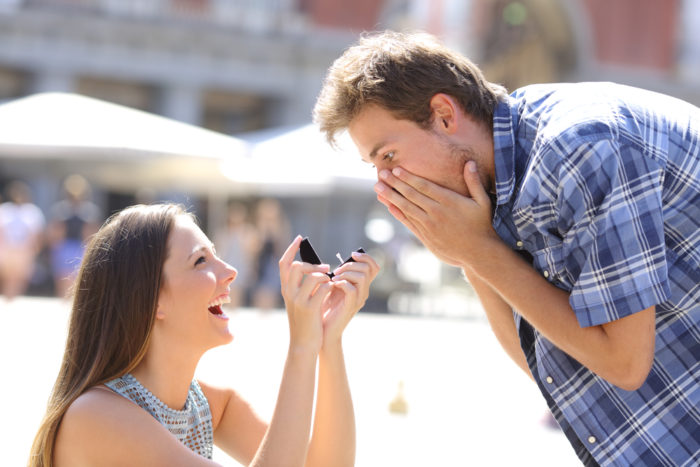 Proposal of a woman asking marry to a man in the middle of a street