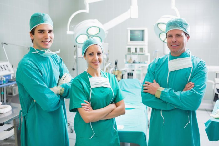 Surgeons standing up with arms crossed in an operating theatre