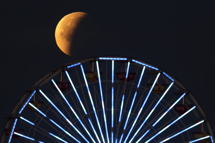 A lunar eclipse of a full "Blue Moon" is seen above the ferris wheel on the Santa Monica Pier in Santa Monica, California, U.S., January 31, 2018. REUTERS/Lucy Nicholson