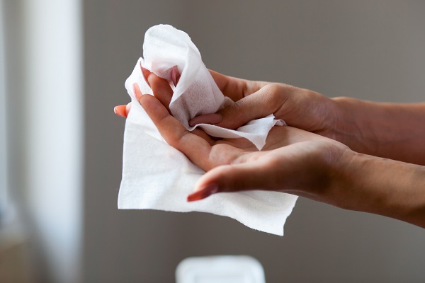 Young woman cleaning fingers and hands with wet wipes
