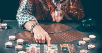 Fortune,Teller,With,Tarot,Cards,On,Table,Near,Burning,Candles.tarot